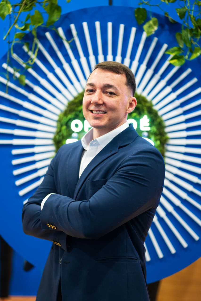 Raphael Machado Donô, de blazer azul-marinho, braços cruzados, sorrindo